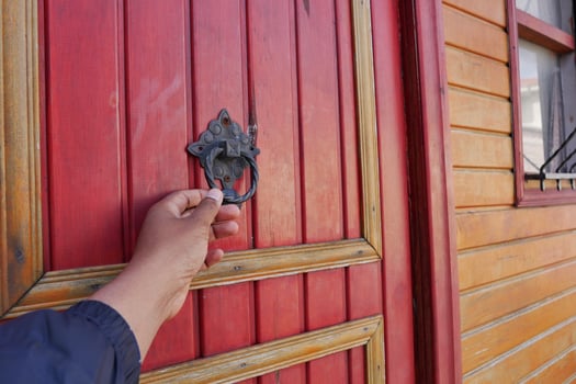Hand reaching for door knocker on wooden door photo