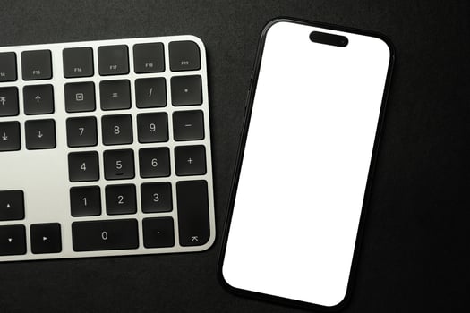 A modern smartphone with a blank white screen rests on a white and black computer keyboard, ideal for showcasing digital content or technology concepts. photo