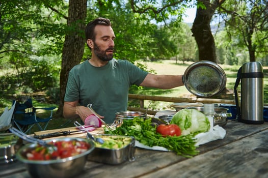 Man Preparing Fresh Ingredients Outdoors at a Picnic Table photo