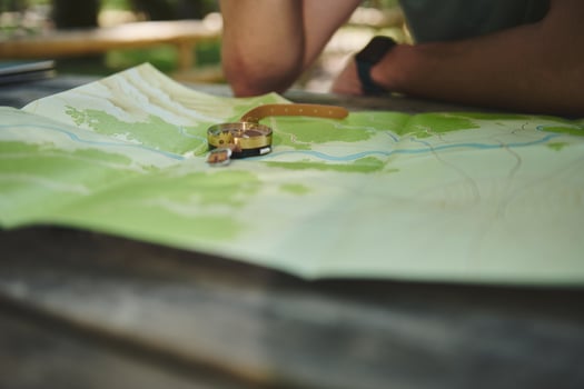 Close-Up of a Map and Compass on a Wooden Table Outdoors photo