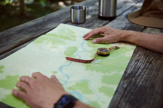 Hands Examining a Topographic Map on a Wooden Table Outdoors photo