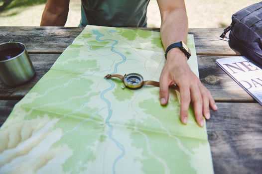 Explorer Planning Path using Map, Compass, Resting at Outdoors Table photo