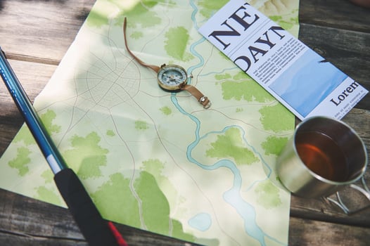Camping Gear Arranged on a Wooden Table Including Map, Compass, and Hiking Pole photo