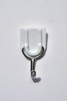 Adhesive wall hook for clothes or towel isolated on vertical white background from top angle view. photo