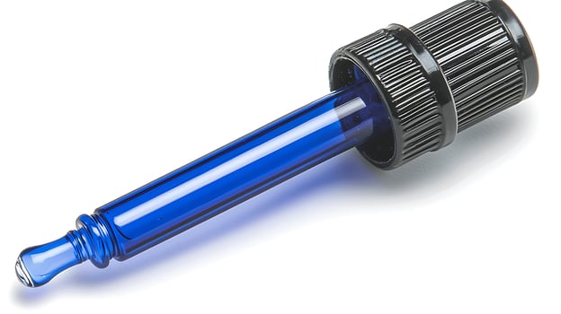 Blue Glass Dropper with Black Cap Isolated on White. A precise tool for dispensing liquids, this blue glass dropper features a textured black cap for a secure grip. photo