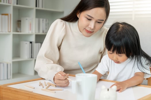 Happy Asian mother playing learning paint for little girl. Funny family is happy and excited in the house. Mother and daughter having fun spending time together. Holiday. photo
