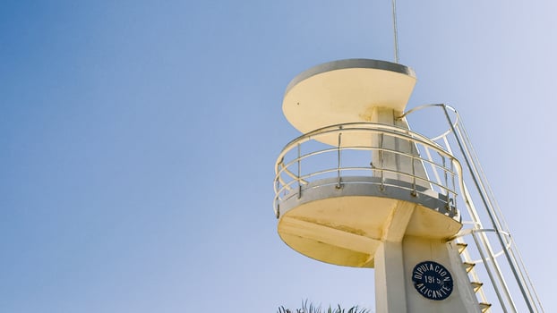 White lifeguard tower stands near palm trees in Alicante, Spain. Image suitable for beach safety, tourism, or coastal architecture context. photo