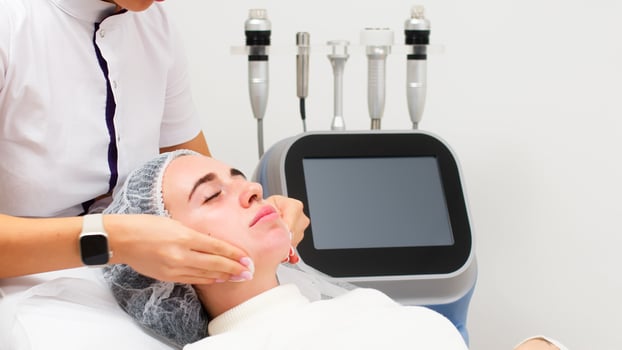 A cosmetologist cleanses the facial skin with napkins before a professional cosmetic procedure in a beauty salon for a client. Skin care and cosmetology spa concept. photo