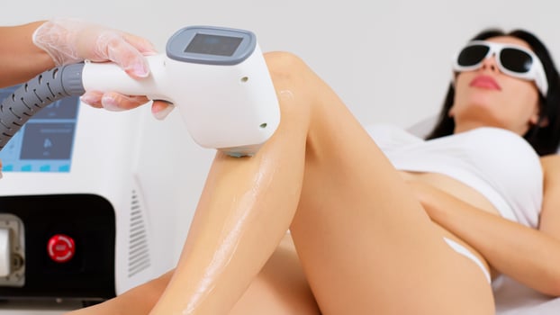 A cosmetologist removes hair on beautiful female legs, epilation for smooth skin, laser procedure in a beauty salon or clinic, epilation for body care. photo