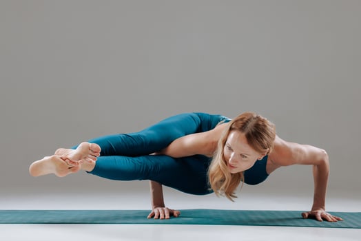 Strong woman performing advanced yoga arm balance on mat showing strength control and flexibility photo