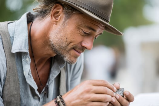 Middle-aged Hispanic male archaeologist examining fossils in vibrant outdoor environment photo