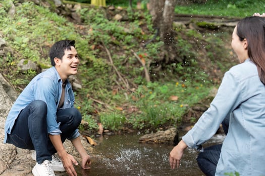 Playful Couple Splashing Water by Stream. Fun moments in nature. photo