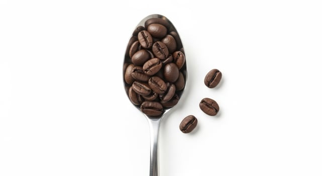 Roasted coffee beans in a silver spoon with scattered beans on a white background top view photo