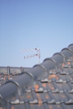 TV antenna on the roof of the house with a clear blue sky in the afternoon photo