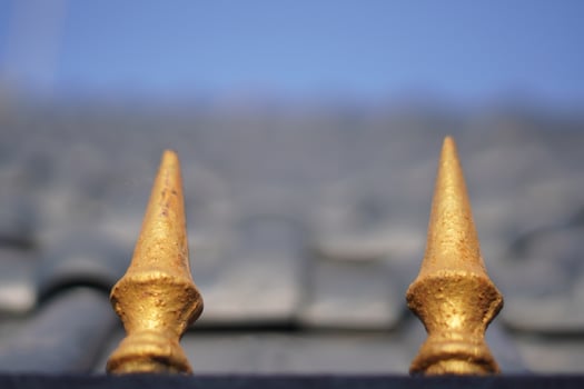 Two golden triangular shaped objects with sharp ends and a blurry blue sky background photo