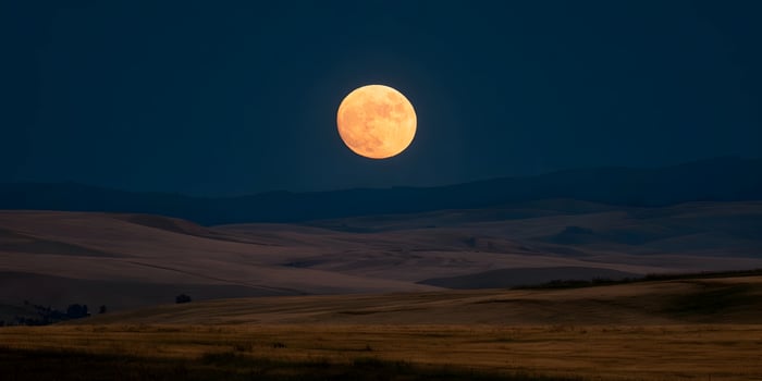 Large Orange Full Moon Over Rolling Hills Landscape at Night photo