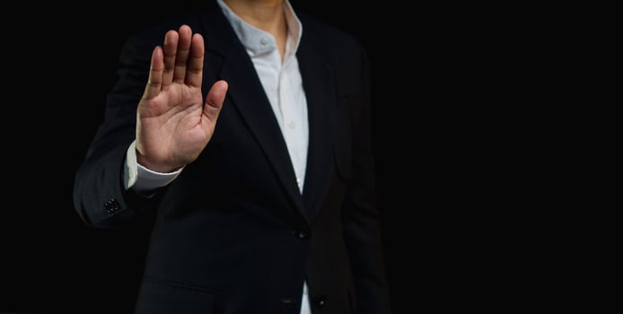 Businessman shows a stop gesture while standing on a black background. photo