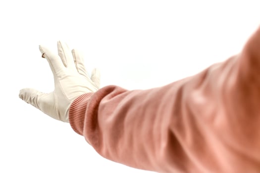 A person wearing a pink sweater and surgical gloves reaching out against white background photo