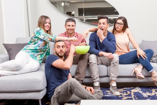 group of young friends having fun watching tv sitting on the sofa eating popcorn photo