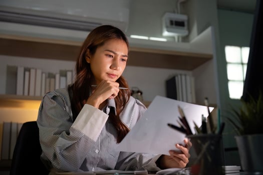 Late Night Reflection. Professional woman contemplating financial data at desk. photo