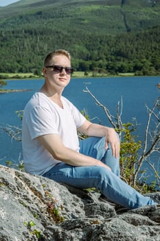 A Relaxing Young Man Enjoys the Peaceful Atmosphere by a Serene Lake Surrounded by Nature photo