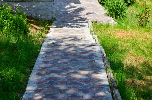 A brick walkway with a shadow cast on it. The shadow is on the ground and the walkway is made of bricks photo