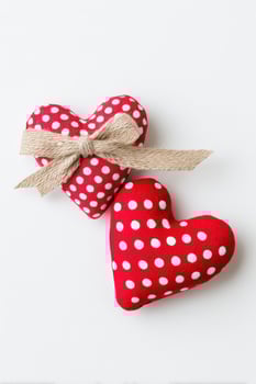 Two decorative red fabric hearts with white polka dots, one tied with a natural burlap ribbon, creating a charming and romantic atmosphere for various occasions photo