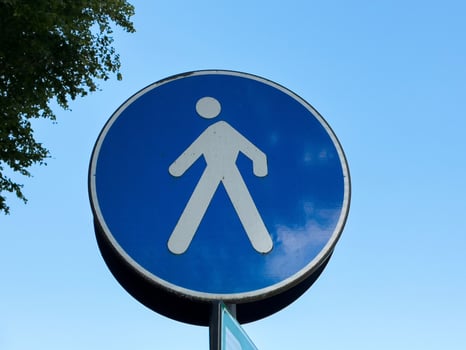 Blue pedestrian sign with white symbol against clear sky photo