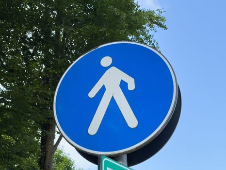 Blue pedestrian traffic sign against clear sky background photo