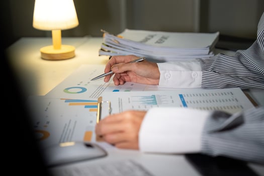 Late Night Analysis. A woman reviewing charts and graphs while working late. photo
