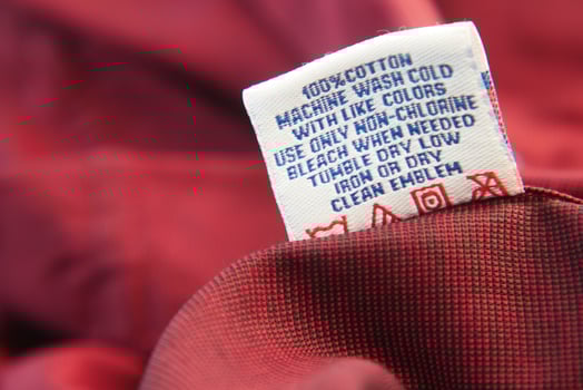 Care instructions label on red fabric close-up shot photo