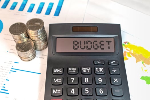 A calculator with the word BUDGET on the display, with coins and business documents photo