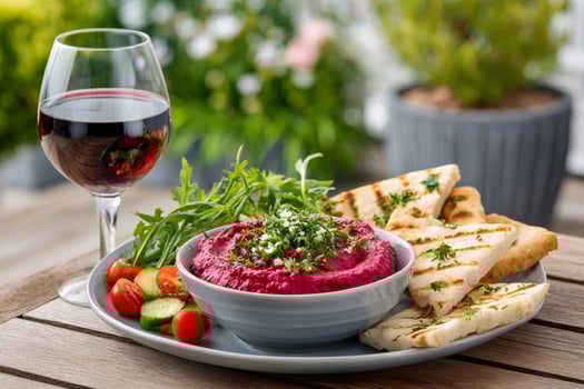 Beetroot hummus with pita bread, fresh vegetables and glass of red wine enjoying a beautiful garden photo
