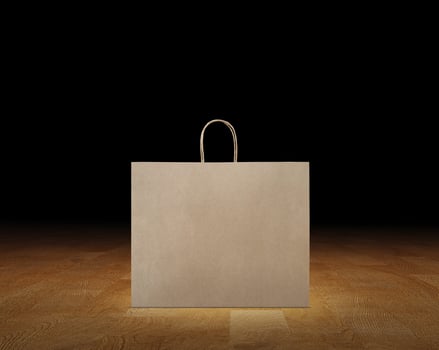 Large empty brown kraft paper bag isolated on wooden surface, black background. photo