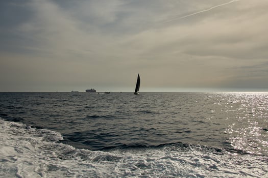 A sailboat sailing on the French Riviera off Marseille, Provence, surrounded by boats and hills under a clear sky photo