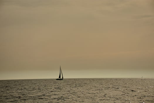 Sailboat sailing the Mediterranean Sea off Marseille, France, with a regatta and the rocky coast of Provence in the background photo