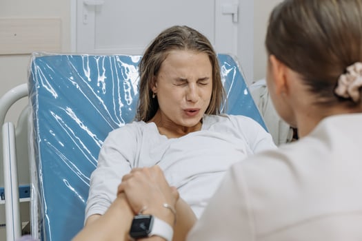 Young woman in labor and contractions in a delivery room on a gynecological chair. Concept of motherhood pain. photo