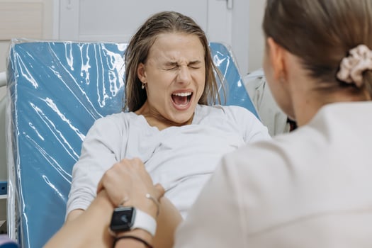 In a delivery room, a young woman is pushing during labor, face tense photo