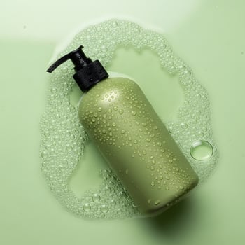 Green Shampoo Bottle in Bubbles, Product Still Life with Soapy Backdrop photo