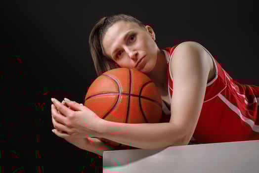 Female Basketball Player Resting with Ball after Game on Dark Background, Professional Sports Concept photo