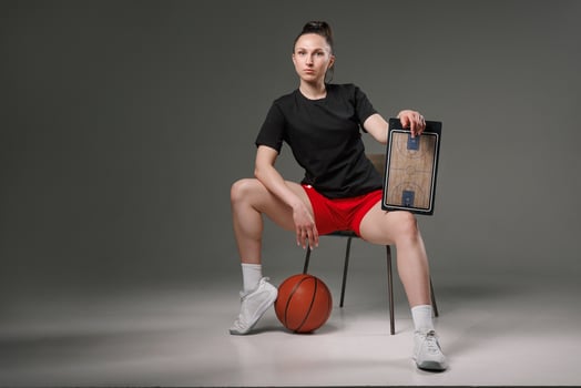 Female basketball coach with tactics board and ball teaching teamwork, strategy, and motivation in professional sports. photo