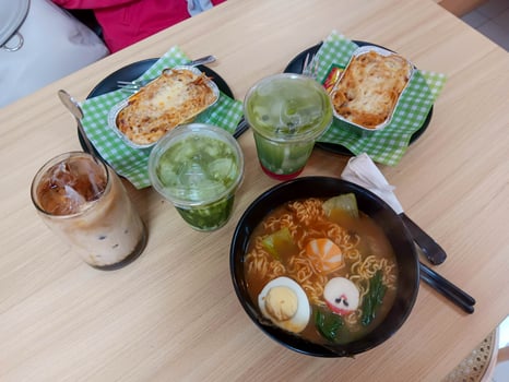 Delicious Asian Fusion Meal Ramen, Lasagna, Matcha, and Iced Coffee on Table. photo