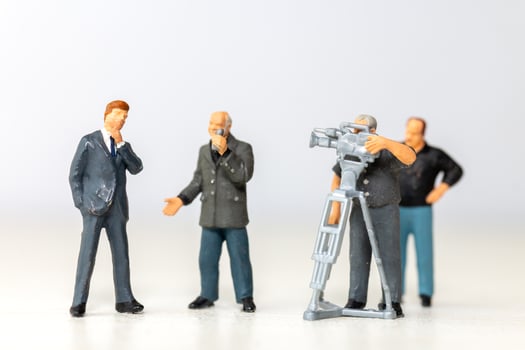 Miniature figure of a male journalist interviewing a businessman with a cameraman recording photo