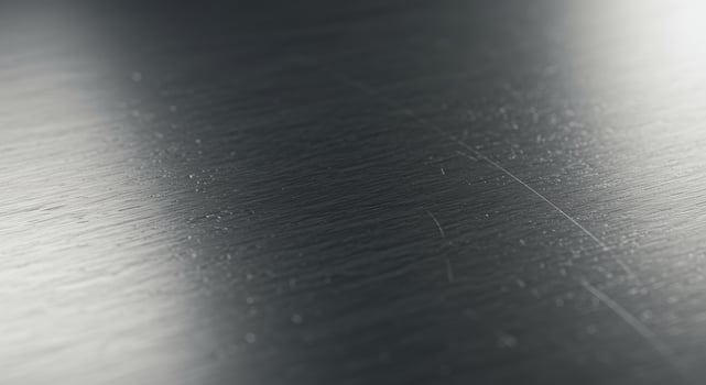 Close up view of a dark gray brushed metal surface showing texture and subtle scratches photo