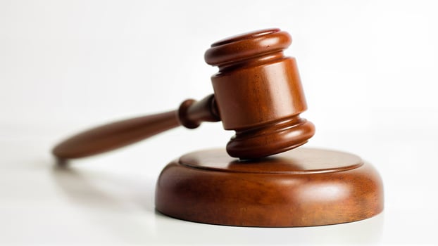 A wooden judge gavel rests on a matching sound block, isolated on a white background. Suitable for legal, justice, court, or law-related content and educational materials. photo
