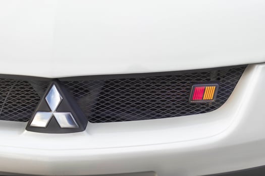 Midday 17.05.2025 Novosibirsk. White Mitsubishi Colt RalliArt logo Close up photo