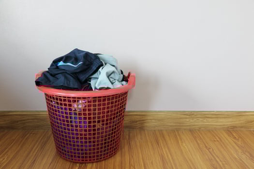 dirty clothes in red basket on wood floor photo