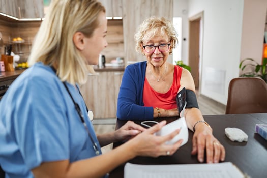 Caring nurse checks blood pressure of elderly woman in home setting photo