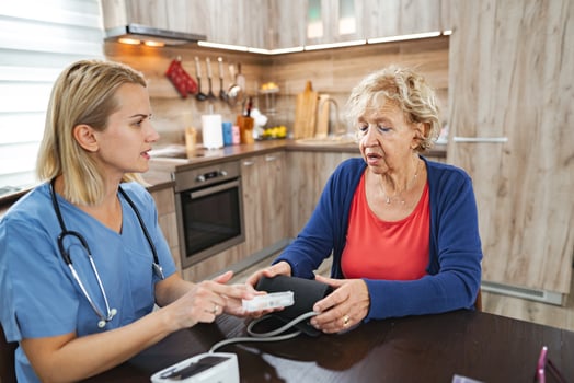 Caregiver checks blood pressure in cozy kitchen setting during afternoon visit photo