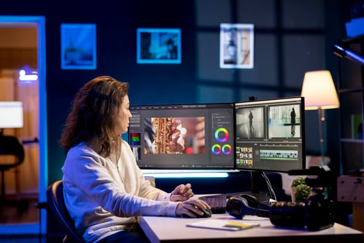 producer adds sound effects to film montage, working in studio. Videographer using headphones to test and improve audio quality using specialized software on computer photo